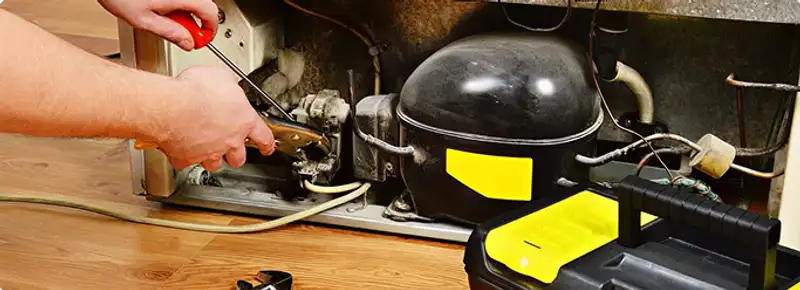 Refrigerator repair technician fixing the compressor and wiring in Prospect, KY