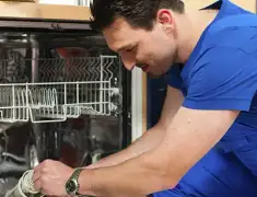 Dishwasher repair technician inspecting and servicing an open dishwasher in Louisville, KY