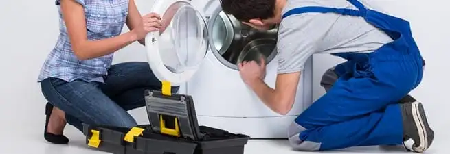Washer repair technician inspecting a front-load washing machine with tools in Louisville, KY