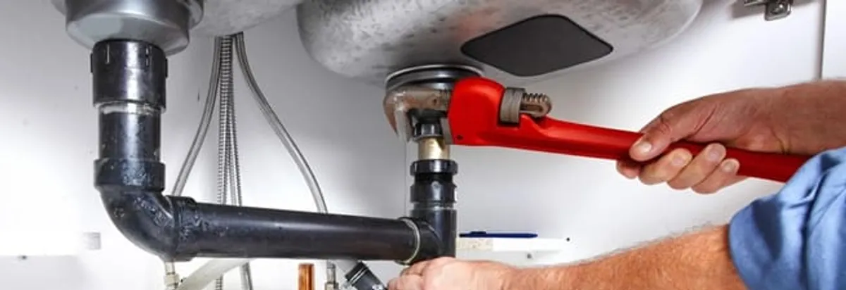 Garbage disposal repair technician tightening the sink drain and disposal connection in Louisville, KY