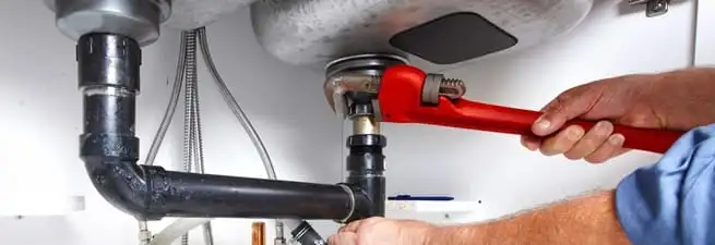 Garbage disposal repair technician tightening the sink drain and disposal connection in Louisville, KY