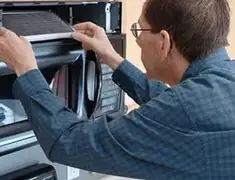 Appliance repair technician replacing a microwave vent filter in Louisville, KY