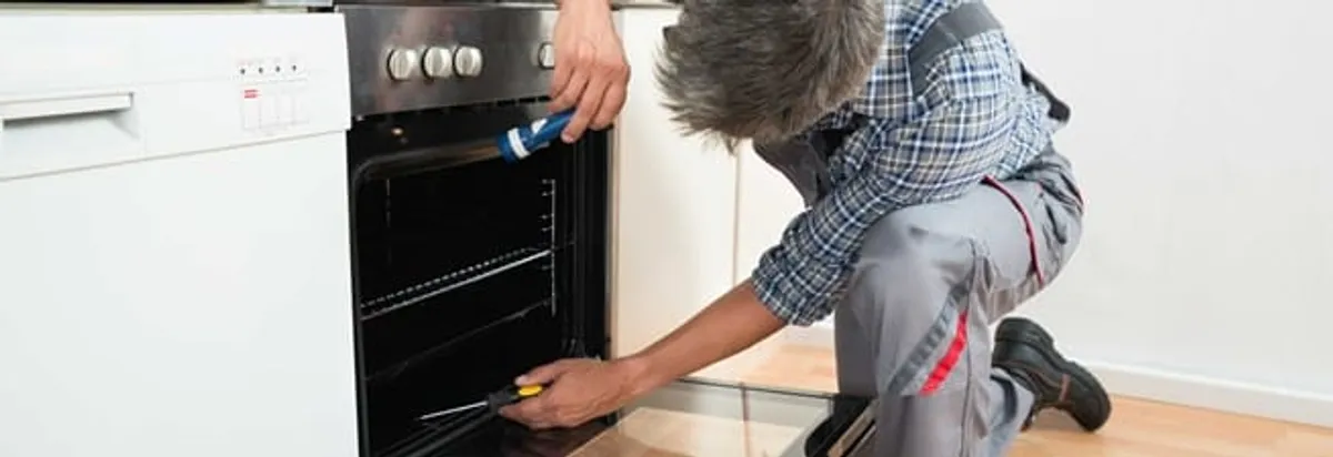 Oven repair technician inspecting and servicing an electric oven in Louisville, KY