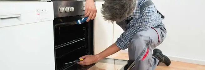 Oven repair technician inspecting and servicing an electric oven in Louisville, KY