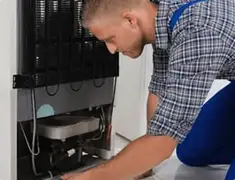 Refrigerator repair technician servicing the compressor and condenser area in Louisville, KY