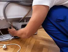 Appliance repair technician fixing refrigerator water line and connections in Louisville, KY