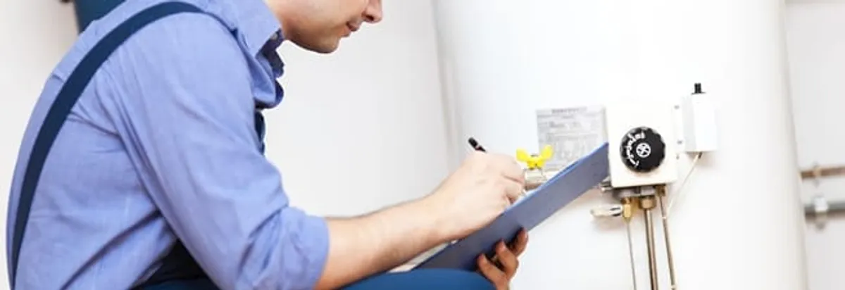Water heater repair technician inspecting the unit and recording service notes in Louisville, KY