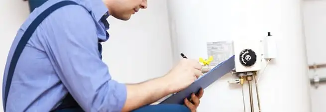 Water heater repair technician inspecting the unit and recording service notes in Louisville, KY